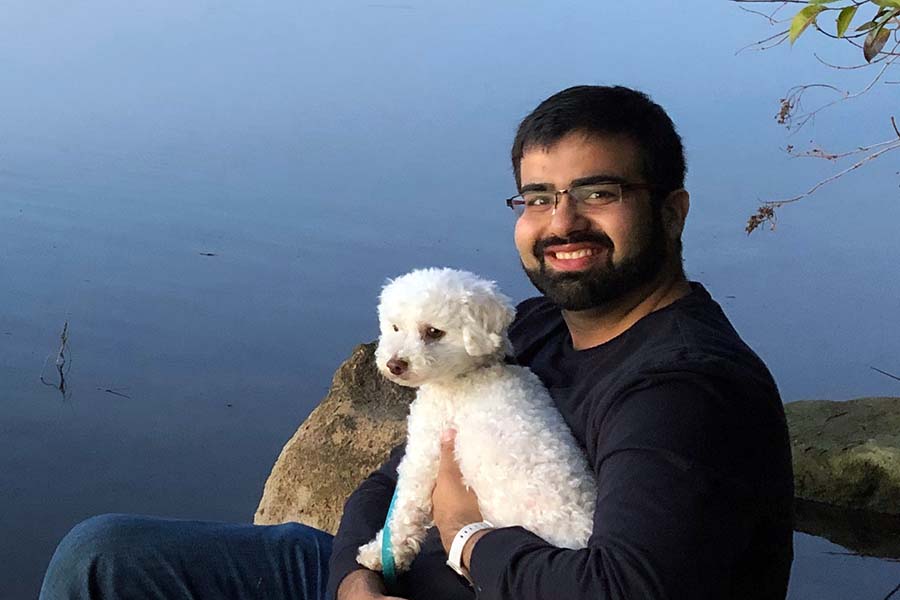 Manish and his dog Pixel sitting by a lake.